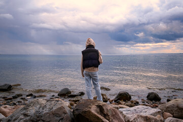 Ein Mädchen steht am Strand und blickt auf das weite Meer - 632604577
