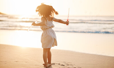 Girl child, bubbles and back by beach in sunset, playing and freedom by waves, games and ocean...