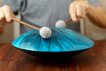 Hands of man musician playing steel tongue drum,music and glucophone instrument. Selective focus