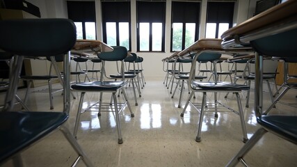 Naklejka na ściany i meble Rows of empty desks chairs in a school classroom towards the back of the room.