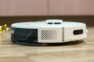 Fototapeta premium White robotic vacuum cleaner on linoleum floors smart cleaning technology. Selective focus