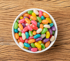 Colorful jelly beans in a bowl over wooden table