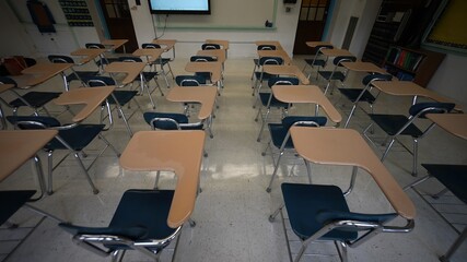 High angle view of rows of empty desks chairs in a school classroom towards the front of the room.
