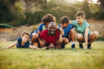 Fototapeta premium School coach and his team lying in a sports field