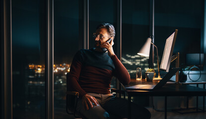Fototapeta na wymiar Entrepreneur's night call: Business communication at office desk