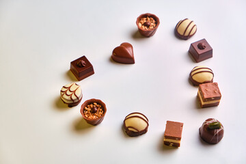 Heart shape made with various types of chocolate truffles over a white table