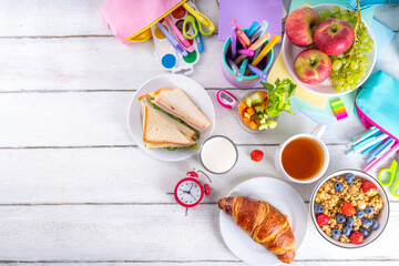 Healthy nutritious  morning breakfast for school kids, with fresh fruits, vegetables, croissant, muesli, milk and sandwich. Having breakfast before school and work, copy space