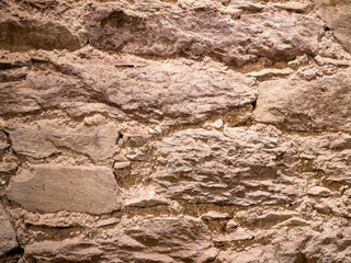Old stone wall pattern close view background, ancient bricks surface. Natural rock wall