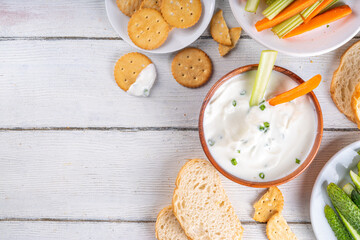 Fototapeta na wymiar Cottage cheese high-protein dip with fresh vegetables, bread and crackers on wooden white table copy space. Eating diet healthy curd cheese spread with various snacks