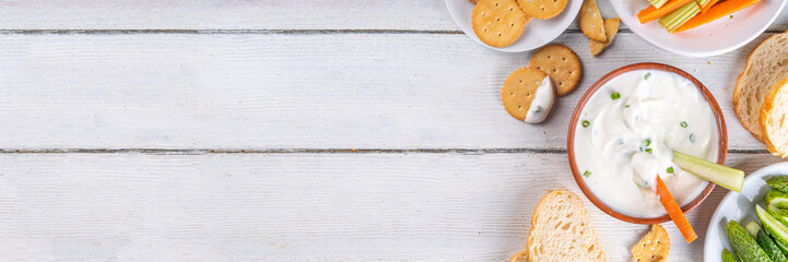 Cottage cheese high-protein dip with fresh vegetables, bread and crackers on wooden white table...