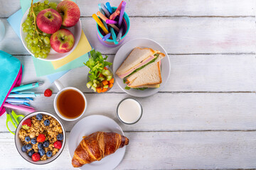 Healthy nutritious  morning breakfast for school kids, with fresh fruits, vegetables, croissant, muesli, milk and sandwich. Having breakfast before school and work, copy space