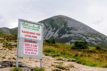 Anti litter sign at foot of Croagh Patrick, with sign for mass on Sunday