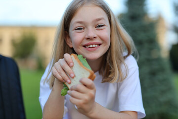 A pupil with a sandwich in their hand during lunch break. They are going back to school and eating a healthy snack.