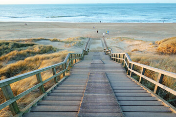 Wooden stairs providing access to a wide sandy beach near Wassenaar, Netherlands.