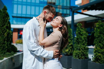 A loving couple, the woman and man, captured in a joyful outdoor portrait. Caucasian Couple Embracing and Laughing Outdoors