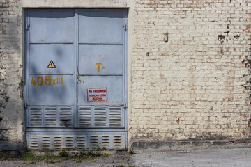 An iron door to an old brick electrical substation with a warning sign in Russian: 