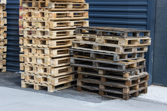 Stacks of old substandard wooden pallets stacked against a warehouse wall