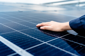 Woman engineer electrician using a hand to check solar panels on the roof, clean energy power nature, photovoltaic systems, the energy produced by the sun, sustainable business concept.