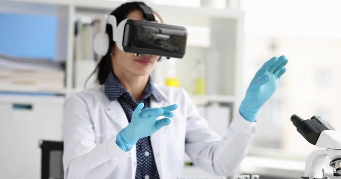 Woman biologist in virtual reality glasses waving hands in laboratory 4k movie. Modern scientific technologies concept