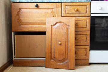 Old wooden kitchen cabinet in the kitchen with a broken door in a Ukrainian apartment, furniture...