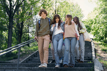 Multiracial Students Chatting While Descending Park Stairs - Teenagers with school gear deeply...