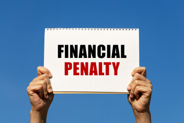 Financial penalty text on notebook paper held by 2 hands with isolated blue sky background. This message can be used as business concept about financial penalty.