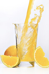 Suco de laranja caindo em copo com pedaços de fruta - Splash em fundo branco