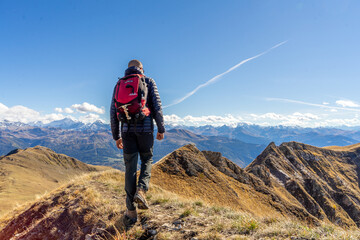 Jeune homme en train de randonner au sommet d'une montagne, en Savoie, dans les Alpes