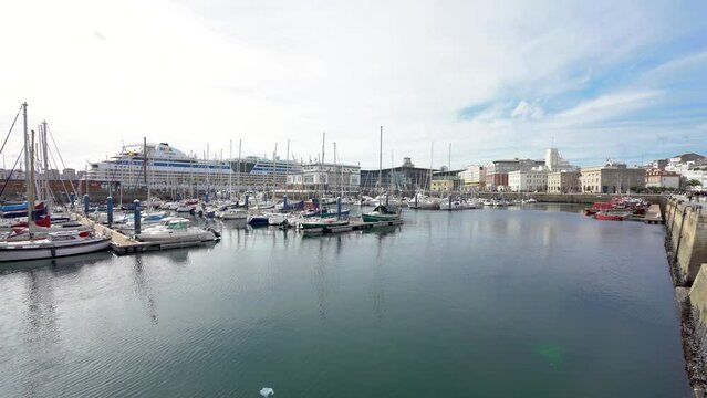 A Coruna, SPAIN - October 30 2022: Spectacular Marina Real Harbour. Beautiful AIDA cruise docked in the bay. Yachts and fishing boats. Travel destination in Galicia, SPAIN. Stabilized. Panning right