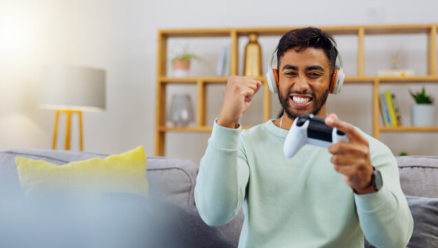 Gaming, winner success and esports with a man in the living room of his home, playing a video game for fun. Winning, celebration and next level with a gamer using a joystick controller to play consol