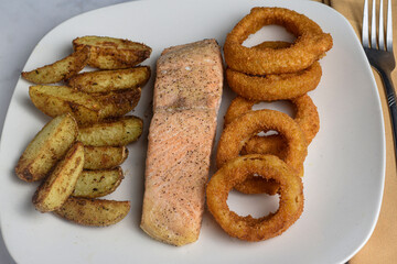 baked salmon  served with onion rings and potato wedges