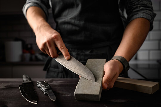 Man sharpening a knife with sharpen stone tool. Master sharpening knife on a grindstone