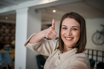 One young woman caucasian looking at the camera, smiling and making selfportrait or a video call