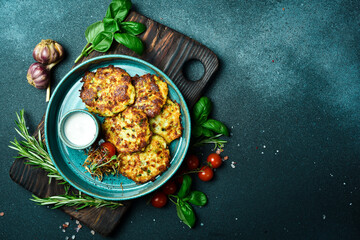 Fried potato pancakes with spinach and sour cream. Ukrainian cuisine. Close up. On a dark stone background.