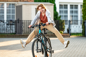 Funny girl riding a bike in the evening in a calm city. Young girl joking and having fun....