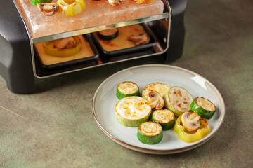 Delicious traditional Swiss melted raclette cheese on diced boiled or baked vegetables served in individual skillets.