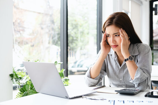 Asian young woman seriously working on computer laptop in office co working space cafe . She thinking find solution problem of work