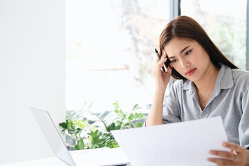 Asian young woman seriously working on computer laptop in office co working space cafe . She...