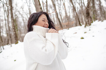 Beautiful woman wearing the white sweater, jeans and hat, the girl in warm cothes. Plus size woman waking, have fun in snow day