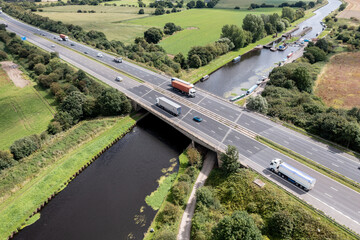 Aerial view directly above a busy UK motorway bridge spanning over a river