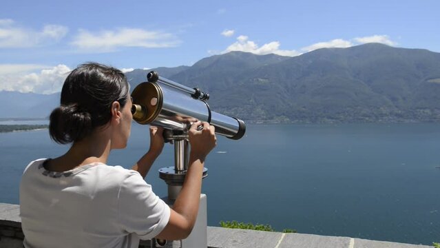 Woman Using a Telescope over Lake Maggiore with Mountain and Brissago Islands in Ticino, Switzerland.