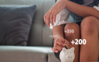 Child holding coin over piggy bank background with money digit number over