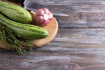 Fresh zucchini, young garlic and herbs on a wooden background, copy space