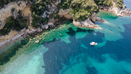 Family snorkeling near boat in clear tropical sea, aerial drone view from above