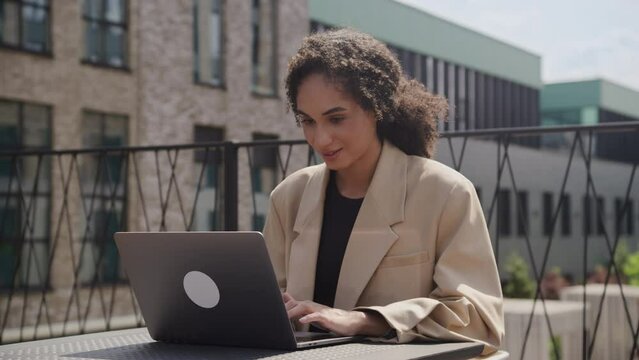 Smiling Woman Typing on Laptop Computer Outdoors