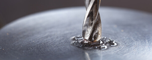 metal drill bit with lubrication oil liquid make holes in steel billet on industrial drilling...