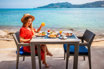 Woman relaxing in luxury hotel, enjoy breakfast with sea view. Vacation girl looking out at the turquoise ocean, tropical resort spa vacation.