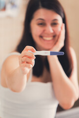 happy woman showing positive pregnancy test