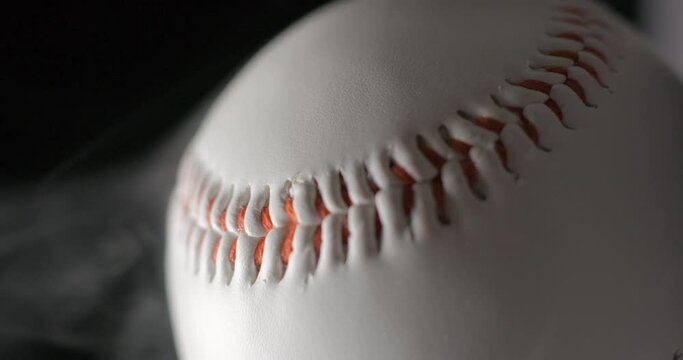 Baseball ball close up rotating in studio with smoke in slow motion, vertical view