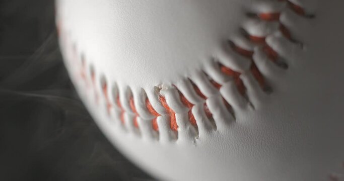 Baseball ball close up rotating in studio with smoke in slow motion, vertical view